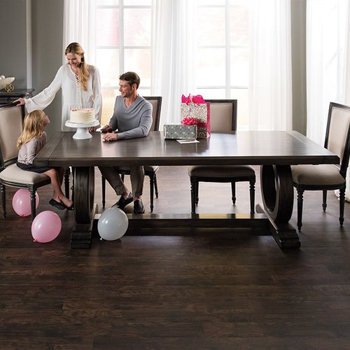 happy family sits at the table in a living room with brown hardwood floor from Johnson & Sons Flooring in Knoxville, TN